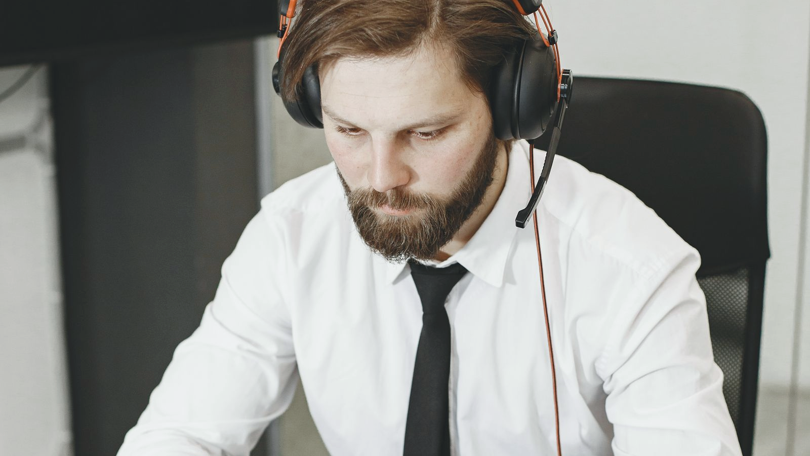 Freight-brokerage-adjacent sales professional with headset at a laptop desk in morning office lighting, readying for the first dial of the day.