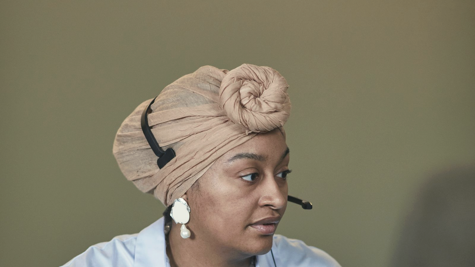 Freight-brokerage-adjacent sales professional with a headset at a desk keyboard, composed expression, notebook and mug nearby.